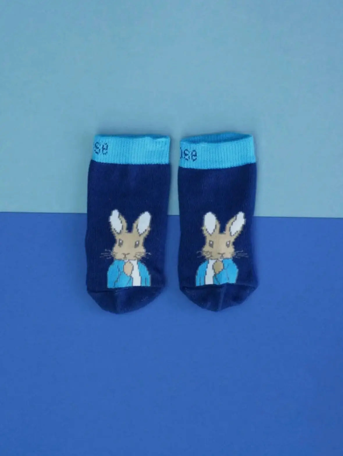 Pair of blue socks with a Peter Rabbit on a blue background